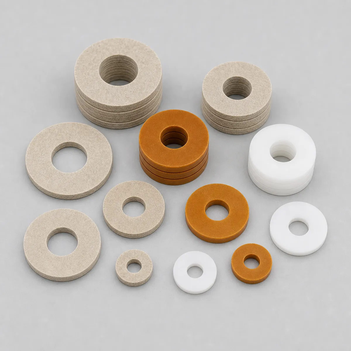 Assorted insulating washers in white, beige, and orange colors on a clean background