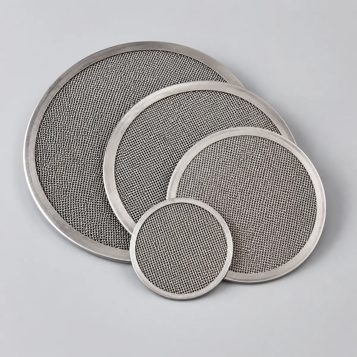 Stainless steel filter discs in different diameters on a light gray background